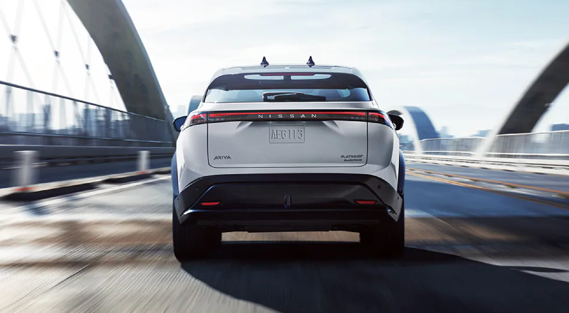 Rearview of a new Nissan Ariya driving over a bridge
